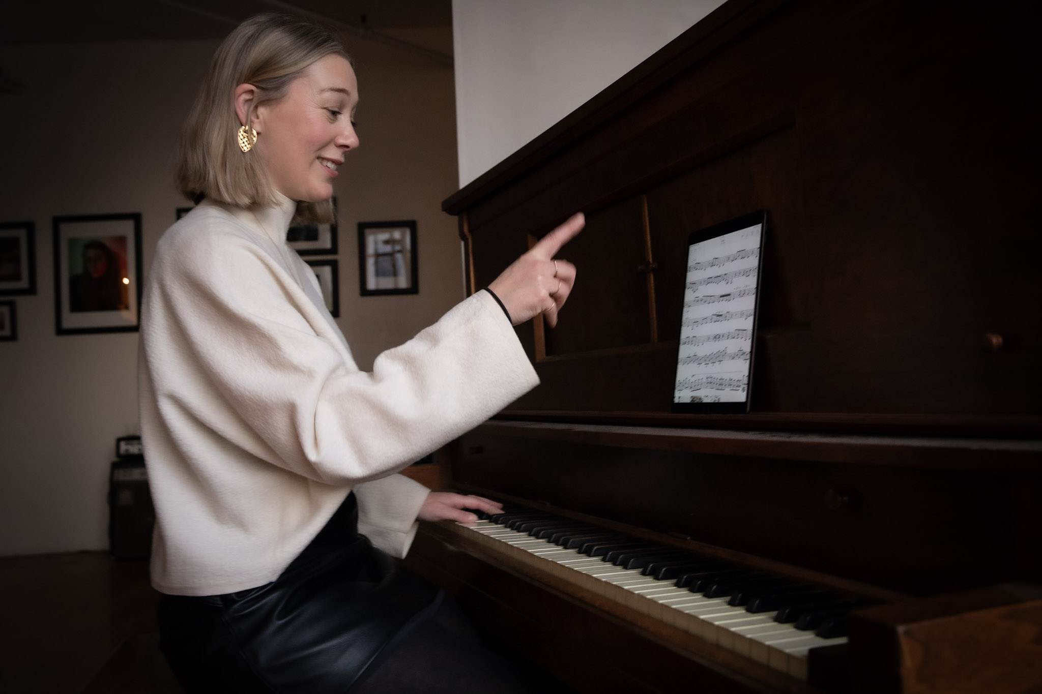 Pianist gesturing toward sheet music on a tablet during a lesson.